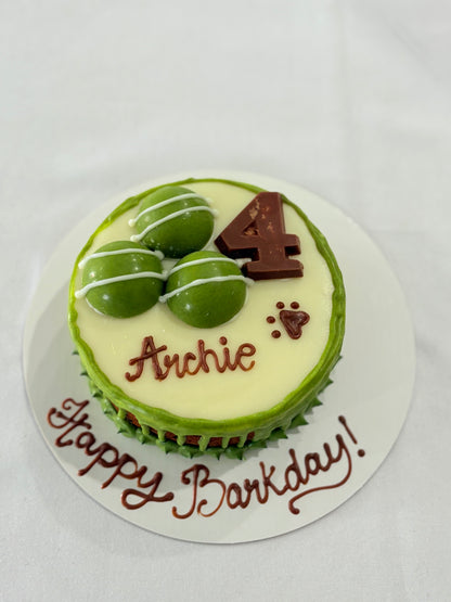 Small round cake with green icing, chocolate number 4, and text 'Happy Birthday Archie' on a white background