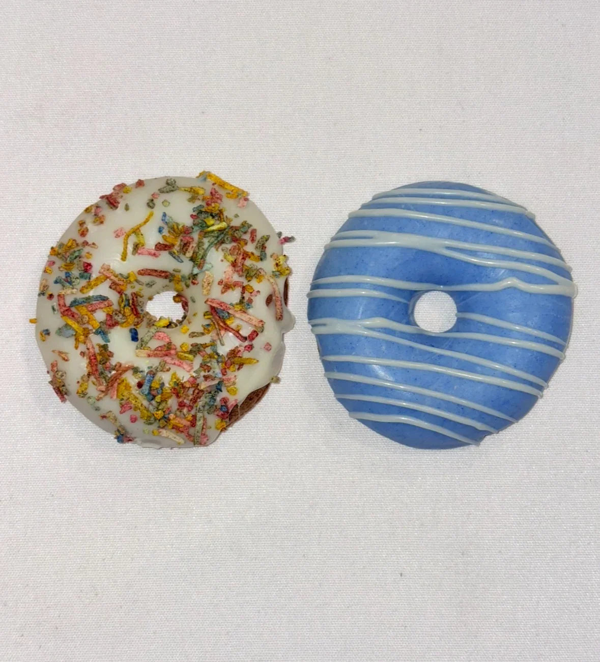 Dog Doughnut, one with colourful sprinkles and the other with blue and white stripes, on a light gray background.